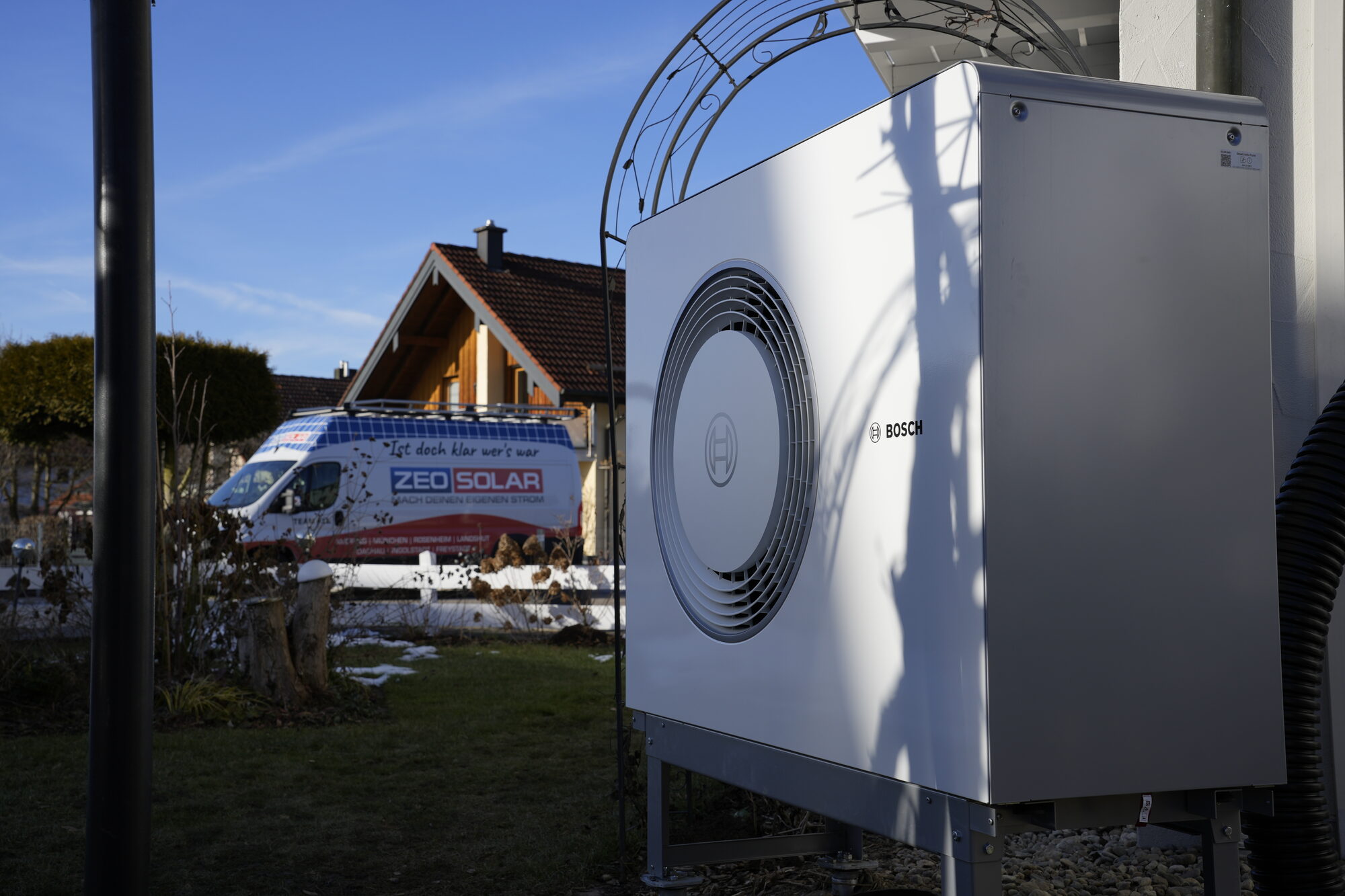 Von ZEO SOLAR installierte Wärmepumpe an einem Einfamilienhaus, im Hintergrund das Firmenfahrzeug